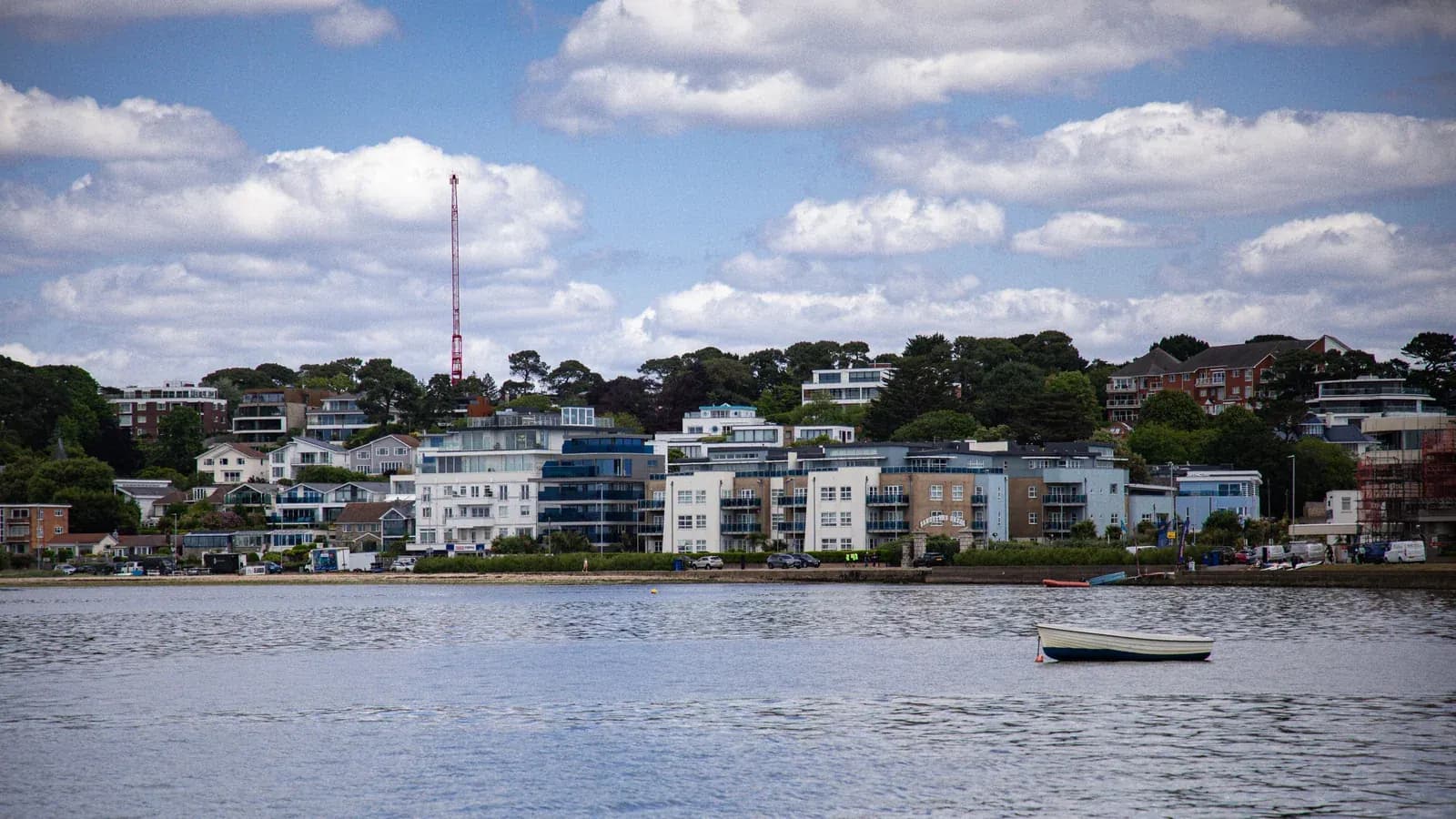 Modern waterfront homes beside Poole Harbour under a bright Dorset sky